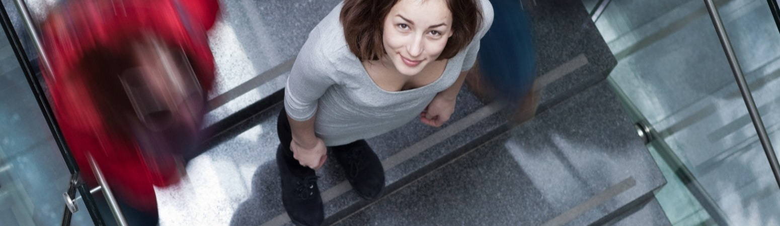 Woman on busy school staircase looking up to camera