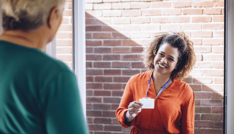 Smiling woman with lanyard stands outside someone's door