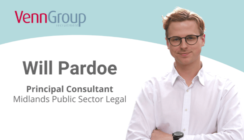 male recruiter in shirt smiling at camera in front of promotion graphic